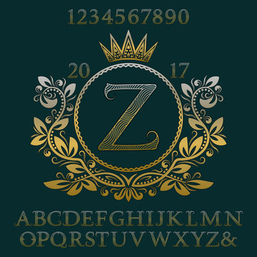 Golden wavy patterned letters and numbers with initial monogram in coat of arms form. Elegant font and elements kit for logo design.