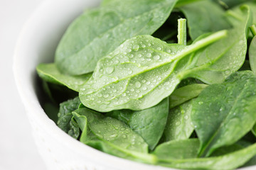 Washed fresh mini spinach in a plate on an stone background