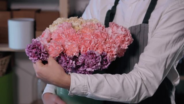 Close up florist hands. man making bunch at flower shop. people, business, sale and floristry concept. Bouquet with roses, peone, lilac and lisianthus