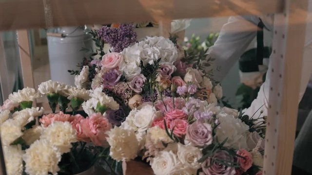 Close up florist hands. man making bunch at flower shop. people, business, sale and floristry concept. Bouquet with roses, peone, lilac and lisianthus