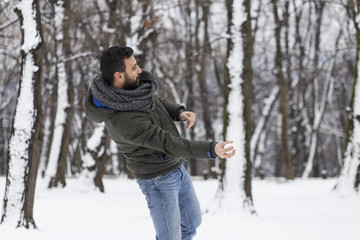 Fototapeta na wymiar Snowball fight. A man throwing a snowball
