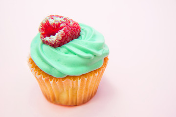 Cupcakes with butter cream and vanilla with raspberry on pink background