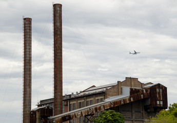 Plane flying past old abandoned industrial factory