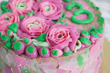 Gorgeous cake covered in roses made of butter cream icing on white wooden background