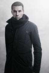 Fashion portrait of young handsome man with scarf and in coat.