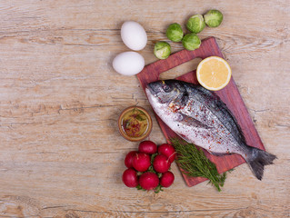dorado fish, radishes, eggs, spices and brussels sprouts on a rustic table