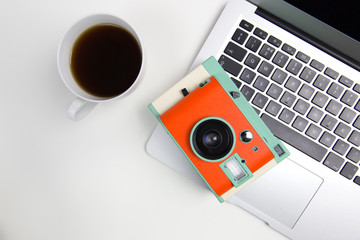 Coffee, camera and laptop computer of white office desk