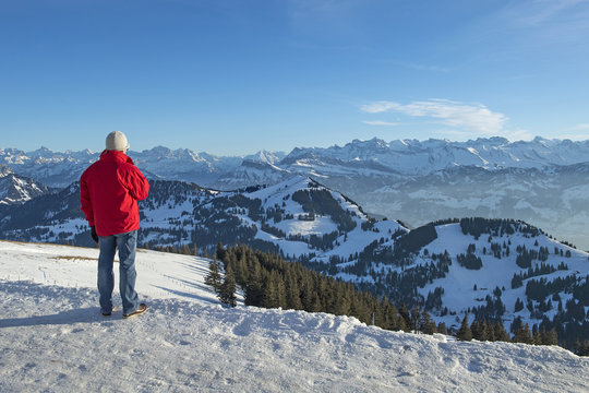 Tourist auf Rigi Kulm geniesst die Aussicht auf die verschneite Bergwelt, Schweiz