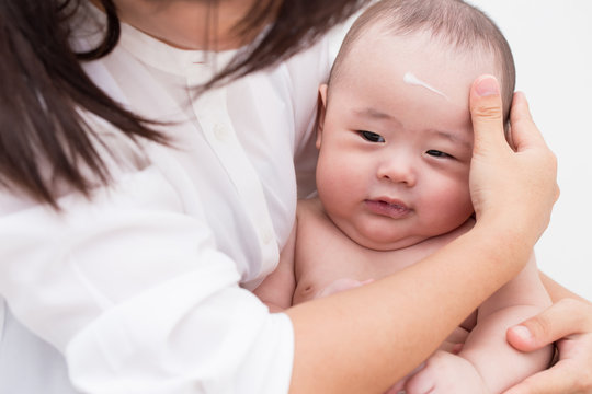 Mother applying baby lotion for son