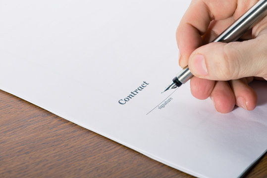 man's hand with a pen sign a contract