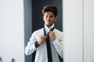 Young business man getting ready in mirror