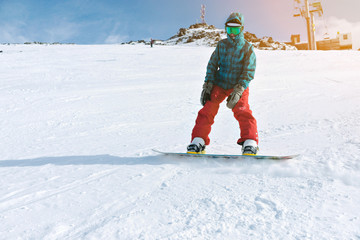 Beginner snowboarder girl wears her google mask and bright clothes, practice her riding skills with backside edge breaking on top of snowy ski slope near lift, isolated on right side