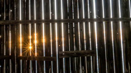 Sonnenstrahlen blinzeln durch Bretterwand