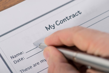man's hand with a pen sign a contract