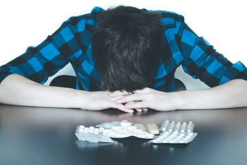 Junger Mann, Tabletten auf dem Tisch, Drogensucht
