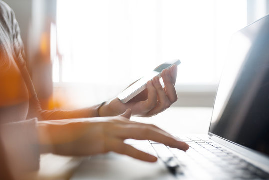 Hands typing information from phone screne on the laptop