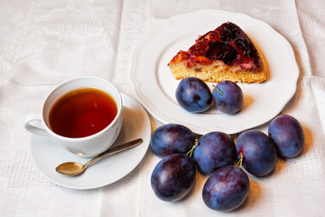 Homemade plum cake and cup of tea on table