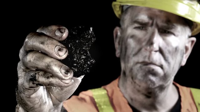 Conceptual video of a coal miner examining a lump of coal just excavated from a mine..
