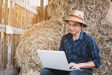 Farmer family with laptop in hay shed.