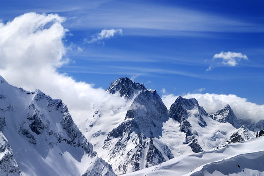 Winter mountains with snow cornice and blue sky with clouds in n