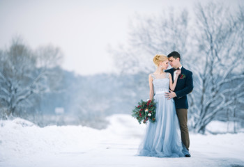 Bride and groom among snowy landscape.