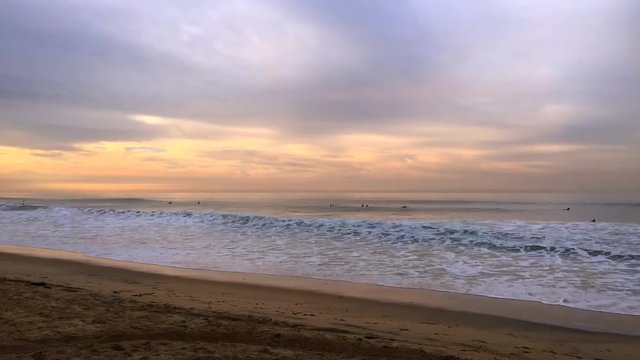 Time lapse of a beautiful beach and ocean waves in Huntington Beach, California framed against a pastel sunrise.