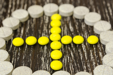 tablets laid out in plus sign outlined circle. On wooden background