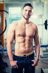 Fototapeta na wymiar Trainierter Sportler zeigt seine Muskeln und seinen Sixpack im Fitness-Club