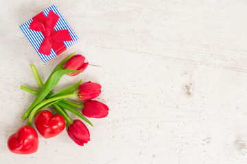 fresh red tulips with two hearts and gift box for valentines day, top view flat lay