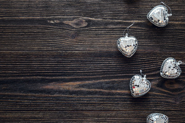 Background with glassy hearts on old dark wooden table. Flat lay
