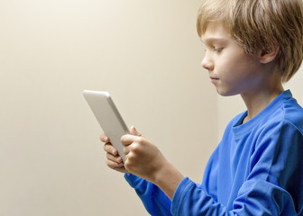 Fototapeta premium Child looking at digital tablet computer and playing online games, learning or reading. Close up