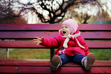 Positive little girl sitting on a bench