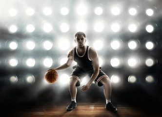 Naklejka premium basketball player on floodlight background and parquet with ball