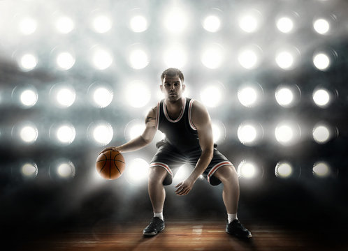 basketball player on floodlight background and parquet with ball