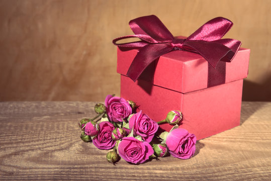 red gift box tied with decorative ribbon and bouquet rose flower
