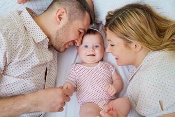 Happy family. Parents with baby on the bed. Closeup.