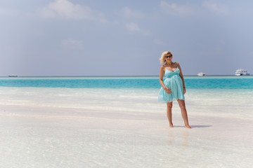 Fototapeta na wymiar Beautiful pregnant girl is walking on sand bank, Maldives