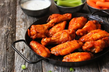 Homemade spicy Buffalo chicken wings served with blue cheese dip celery sticks and baby carrots on...