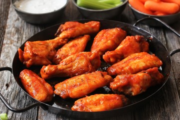 Homemade spicy Buffalo chicken wings served with blue cheese dip celery sticks and baby carrots on...