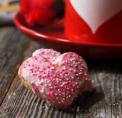 Homemade Heart cookies with pink icing and sprinkles on valentine background, selective focus