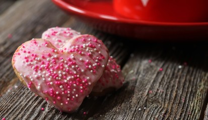 Homemade Heart cookies with pink icing and sprinkles on valentine background, selective focus