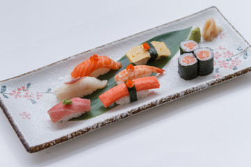 Sushi Set Include Maguro, Hamachi, Salmon, Kani, Shrimp, Tamagoyaki and Salmon Maki Roll Served with Wasabi and Prickled Ginger on Japanese Painted Stone Plate.
