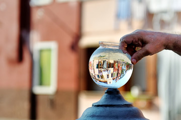 Burano buildings picturesque view from a round glass bowl full of water, Venice