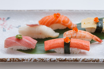 Sushi Set Include Maguro, Hamachi, Salmon, Kani, Shrimp, Tamagoyaki and Salmon Maki Roll Served with Wasabi and Prickled Ginger on Japanese Painted Stone Plate.