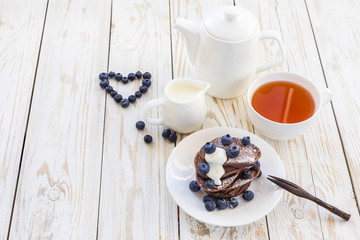 Hot tea and buckwheat chocolate pancakes with blueberries