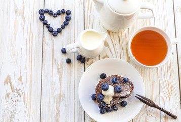 Hot tea and buckwheat chocolate pancakes with blueberries