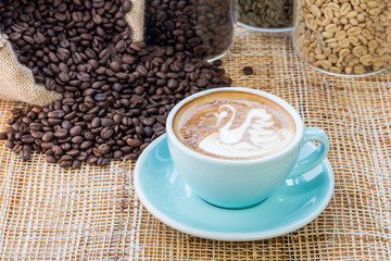 Cup of coffee on coffee beans background on a wooden table