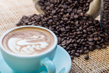 Cup of coffee on coffee beans background on a wooden table