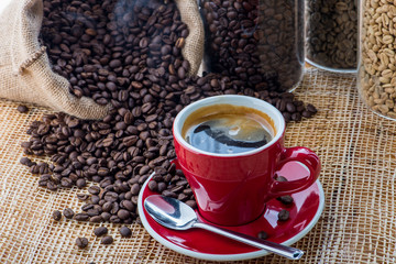 Cup of coffee on coffee beans background on a wooden table