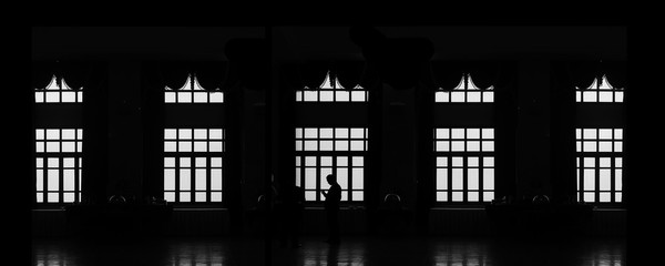 silhouette glass window home with a man, selective focus on the middle glass window, processed in black and white or monochrome. silhouette of a grand ball room with glass windows